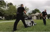  ?? RICARDO RAMIREZ BUXEDA/ORLANDO SENTINEL ?? Left to right, Apopka police officers Justin Lemieux and Matt Reinhardt mow a lawn in Apopka on Wednesday. Rodney Smith Jr. provides free lawn care to those in need.