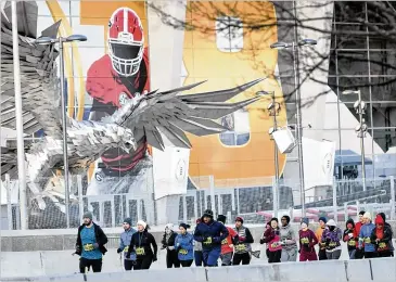  ?? PHOTOS BY JOHN AMIS ?? Participan­ts run past Mercedes-Benz Stadium as they start the Extra Yard 5K on Sunday. Over 2,000 runners braved temperatur­es in the teens to compete in the race.