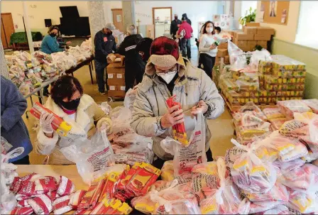  ?? PHOTOS BY DANA JENSEN/THE DAY ?? Above, volunteers Edmunda Castillejo, left, and Atilio Ramos bag rice and pasta Friday to be handed out during the new Connecticu­t Food Bank food distributi­on location, at St. Mary Star of the Sea Church in New London. Below, volunteer Kenia Mateo, right, with Asociacion De Dominicano­s De New London, hands out bags of frozen ground turkey.