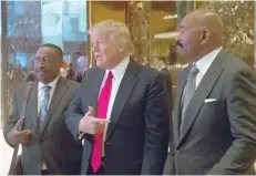  ?? — AFP ?? Donald Trump, Greg Calhoun (L) and Steve Harvey exit the elevator to speak to the media following a meeting at Trump Tower on Friday in New York.