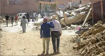  ?? MOSA’AB ELSHAMY/AP ?? Residents walk through quake wreckage Sunday in the town of Amizmiz near Marrakech, Morocco. The epicenter was near the town of Ighil in Al Haouz Province, about 44 miles south of Marrakech. The region is known for scenic villages and valleys in the High Atlas Mountains.