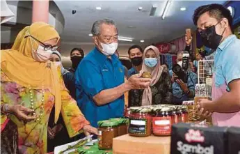  ?? BERNAMA PIC ?? Prime Minister Tan Sri Muhyiddin Yassin (second from left) and his wife Puan Sri Noorainee Abdul Rahman (left) visiting a booth at the Prihatin and Penjana programme at Medan Niaga Satok in Kuching yesterday.
