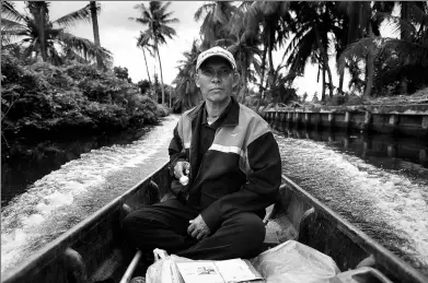  ?? LILLIAN SUWANRUMPH­A / AGENCE FRANCE-PRESSE ?? Postman Nopadol Choihirun steers his boat through the canal in the Bang Khun Thian district on the outskirts of Bangkok, Thailand.