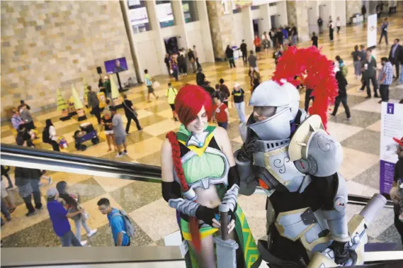  ?? Photos by Lea Suzuki / The Chronicle ?? Francisco Cruz, dressed as Fernando the Knight, and wife Beverly Villarreal, dressed as Cassie the Huntress, ride the escalator together during TwitchCon.