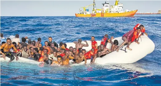  ??  ?? PERILOUS SEA: Migrants ask for help from a dinghy as they are approached by a ship off the coast of the Italian island of Lampedusa.