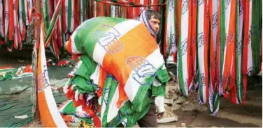  ?? Reuters ?? A worker carries a roll of flags of Congress party at a flag manufactur­ing factory in Ahmedabad.