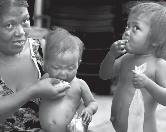  ?? SUNSTAR FOTO/ALEX BADAYOS ?? 1,000 DAYS. Maria Lourvie Abesia feeds her four-year-old and one-yearold daughters “tuslob-buwa,” or hanging rice dipped in a frying pan containing pig brains, pork stock and oil, in Barangay Sawang Calero, Cebu City. The children’s distended stomachs show their malnutriti­on. Of Abesia’s seven children, two died before reaching the age of two. The National Nutrition Council’s Early Childhood Care and Developmen­t Interventi­on Package for the First 1,000 Days aims to secure children’s health from conception to their first two years of life.