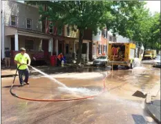  ??  ?? A Pottstown Public Works crew power washed mud off the intersecti­on of Manatawny and Walnut Street Friday. On Thursday afternoon, it was under 5 feet of water.