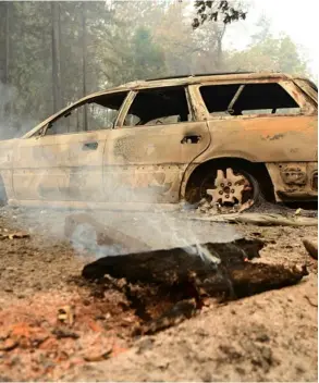  ?? AFP ?? Un tronco arde frente a un carro quemado durante un incendio en el condado de Shasta, al sur de Lakehead, California, este viernes.