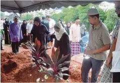  ??  ?? AZIMAH (tengah) di sisi kubur suaminya.