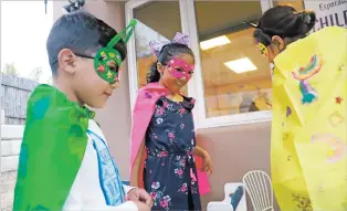  ??  ?? Ashley and Oscar Jimenez admire the finished superhero cape of another child from Seeds of Hope on Oct. 22. The children were asked to make capes representi­ng their strength or superpower as a Halloween activity.