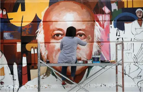  ?? AFP ?? Iraqi artist Wijdan Al Majed paints a mural depicting Iraqi poet Muzzafar Al Nawab on a building in Baghdad