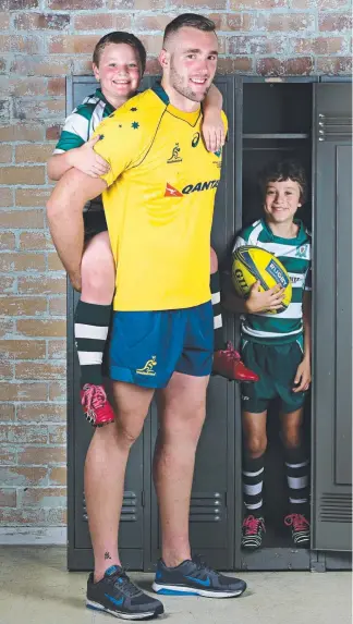  ?? Picture: ANNETTE DEW ?? New Wallaby Izack Rodda, a giant at 2.02m, stands with Ipswich footy juniors William Foote and Oscar Graves, both 8.