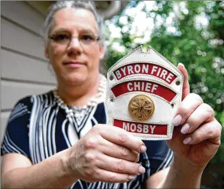  ?? STEVE SCHAEFER / FOR THE AJC ?? Rachel Mosby shows part of her old Byron fire chief’s uniform at her Decatur home in June. In the job more than a decade, she began medically transition­ing in 2016. She sued alleging firing due to the city’s “discrimina­tory animus based on her sex, gender identity, and notions of sex stereotypi­ng.”