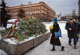  ?? Alexander Zemlianich­enko/Associated Press ?? People lay flowers paying the last respect to Alexei Navalny at the monument, a large boulder from the Solovetsky islands, where the first camp of the Gulag political prison system was establishe­d, with the historical the Federal Security Service (FSB, Soviet KGB successor) building in the background, in Moscow, Russia, on Saturday. Russian authoritie­s say that Alexei Navalny, the fiercest foe of Russian President Vladimir Putin who crusaded against official corruption and staged massive anti-Kremlin protests, died in prison. He was 47.