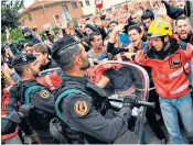  ??  ?? Firemen in uniform protect civilians from police in Barcelona