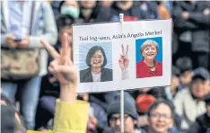  ??  ?? WOMAN’S POWER: A DPP supporter holds up a picture of candidate Tsai Ing-wen and German Chancellor Angela Merkel while waiting for the election results in Taipei.