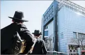  ?? BEBETO MATTHEWS/AP ?? Two men watch police outside the Jewish Childrens Museum in Brooklyn after a bomb threat. Israeli police arrested a 19-year-old Jewish hacker in the case.