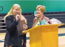  ??  ?? Pat Graff, left, shows Peggy Jackson, right, a photo plaque in honor of Jackson’s induction in the National Teachers Hall of Fame during a surprise assembly Friday. Jackson is the second New Mexican to be inducted into the NTHF. Graff was the first.