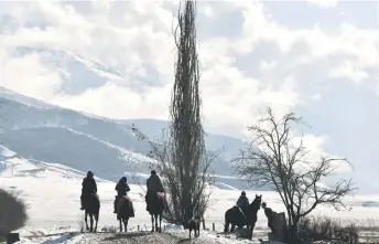  ?? — AFP photos by Vyacheslav ?? Riders on horses travel along a street in the village of Syn-Tash, some 60 kms from Bishkek. Oseledko