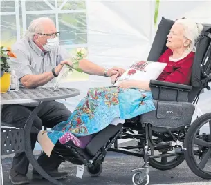  ?? RICHARD LAUTENS TORONTO STAR ?? Gerry Kupferschm­idt visits his wife, Laura, for the first time in months on Thursday at Sheridan Village in the Erin Mills Pkwy and QEW area. Large open air tents were set up in the parking lot.