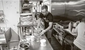  ?? Ricardo B. Brazziell / TNS ?? Shawn Faulk prepares food for a to-go order at Star Coffee in Round Rock. Full-service restaurant prices rose a record 0.9 percent in June.