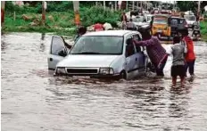  ?? PTI ?? People push a car through a flooded road after a heavy downpour in Hyderabad.