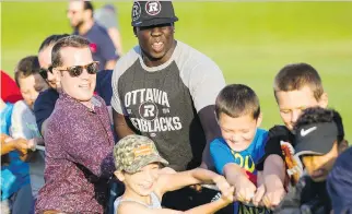  ?? DARREN BROWN ?? City councillor Mathieu Fleury, left, and the Redblacks’ Ron Omara join some North Gloucester Giants players in a tug of war after a ceremony to mark an equipment donation by Mattamy Homes.