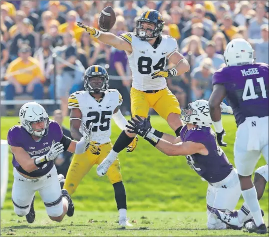  ?? [JIM YOUNG/THE ASSOCIATED PRESS] ?? Iowa’s Nick Easley leaps for a loose football over Northweste­rn’s Paddy Fisher during the Wildcats’ overtime win.