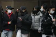  ?? ANDY WONG — THE ASSOCIATED PRESS ?? Office workers wearing protective face masks take their lunch break in Beijing, Monday, Feb. 24. China says it is postponing its most important political meeting of the year because of the outbreak of the new virus.