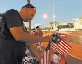  ?? Blake Apgar ?? Las Vegas Review-journal @blakeapgar Steve Round, 47, adjusts flags Wednesday at a memorial site near the “Welcome to Fabulous Las Vegas” sign.