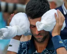  ??  ?? Novak Djokovic, of Serbia, puts an ice towel around his head during a changeover against Joao Sousa, of Portugal, during the fourth round of the U.S. Open tennis tournament, on Monday, in New york.AP PhoTo/cArolyn kASTer