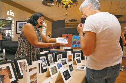  ??  ?? LEFT: Contempora­ry Pueblo artist Michele Tapia-Browning of Pojoaque and Santa Clara pueblos displays her digital photo collages during the Free Indian Market Show.