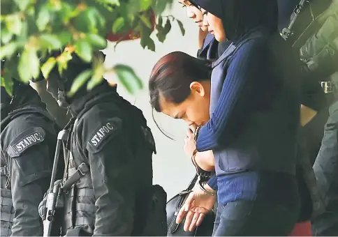  ?? — Reuters photo ?? Indonesian Siti Aisyah, who is charged for the murder of Kim Jong Nam, is escorted by police as she leaves a Sepang court.