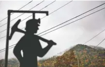  ?? ASSOCIATED PRESS FILE PHOTO ?? Fog hovers over a mountainto­p as a cutout depicting a coal miner stands at a memorial to local miners killed on the job in Cumberland, Ky.