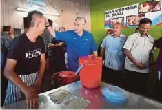  ??  ?? AHMAD Zahid beramah mesra dengan penebar roti canai ketika tiba pada Majlis Sarapan Pagi Bersama Masyarakat Setempat di Warong Kopi Atan Deris di Bagan Datuk, semalam.