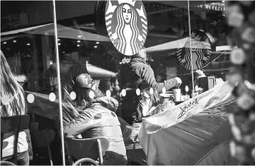  ??  ?? Customers sit inside a Starbucks coffee shop in Shanghai, China, on Jan 24, 2016.