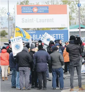  ?? RYAN REMIORZ, THE CANADIAN PRESS ?? Striking Canada Post workers walk the picket line in front of the Saint-Laurent mail-sorting facility in Montreal on Tuesday.