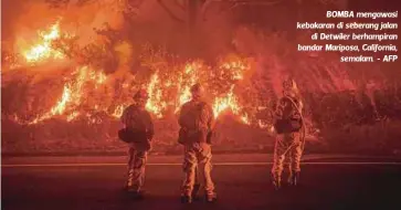  ??  ?? BOMBA mengawasi kebakaran di seberang jalan
di Detwiler berhampira­n bandar Mariposa, California,
semalam. - AFP