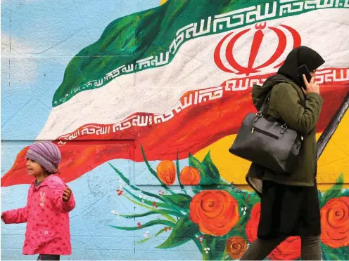  ?? Foto: AFP/ Atta Kenare ?? Eine Frau läuft in Teheran an einer patriotisc­hen Wandmalere­i vorbei.