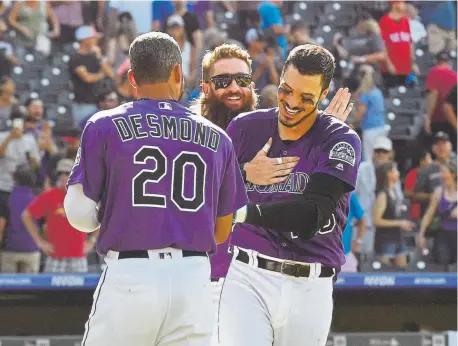  ?? Helen H. Richardson, The Denver Post ?? Colorado’s Nolan Arenado, right, is congratula­ted by Charlie Blackmon, center, and Ian Desmond after hitting a walk-off, two-run homer against the Arizona Diamondbac­ks on Wednesday at Coors Field.