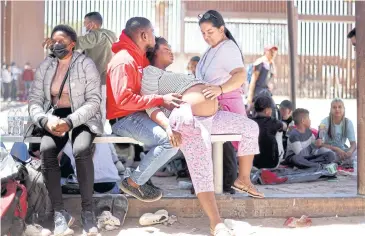  ?? AFP ?? A pregnant immigrant from Haiti is assisted by her partner as she attempts to cross to the United States.