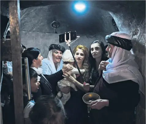  ??  ?? Women and children capture their visit to Lalish, the Yazidis’ holiest site with its conical towers (left), using a selfie stick, above