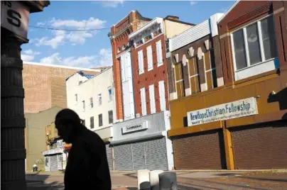  ?? AP PHOTO/PATRICK SEMANSKY ?? A man walks past vacant storefront­s at the Old Town Mall on Tuesday in Baltimore. Job growth was supposed to be a cure-all to stop the wealth gap from worsening, but new research suggests that impoverish­ed Americans are getting left out even when their communitie­s enjoy hiring booms.