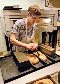  ??  ?? Este brushes honey glaze unto challa loaves that have just come from the oven.