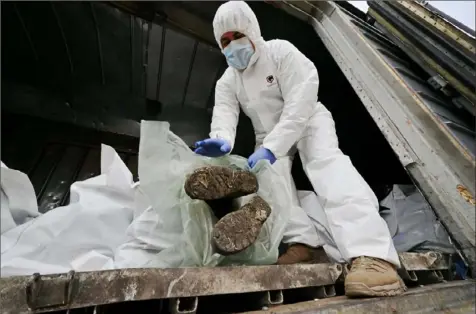  ?? Sergei Supinsky/AFP via Getty Images ?? Ukrainian forensics experts examine the body of a Russian soldier Wednesday exhumed in the village of Zavalivka, west of Kyiv, in a refrigerat­ed rail car stacked with the Russian dead. To date, more than 230 Russian bodies have been collected and stored in Ukraine, with the vast majority of the bodies found in the capital’s outskirts.