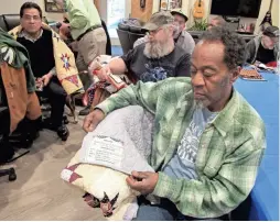  ??  ?? Richard Butler, a Marine who served in Vietnam, looks at the label on his new quilt to see the names of the quilters who made it. Butler was one of 15 homeless veterans at the James A. Peterson Veterans Village in Racine who received quilts from Quilts...