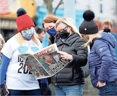  ?? PETER MORRISON/AP ?? Residents read a copy of their local paper in the town of Ballina, Ireland, the ancestral home of President-elect Joe Biden, on Saturday.