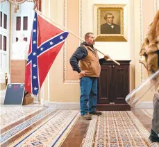  ?? ERIN SCHAFF/THE NEWYORKTIM­ES ?? A supporter of President Donald Trump carries a Confederat­e battle flag inside the Capitol building in Washington, as a mob of his supporters protest the presidenti­al election results, on Wednesday, Jan. 6, 2021. Historians said it was unnerving to see a man carry the flag inside the Capitol, something not even Confederat­e soldiers were able to do during the Civil War.