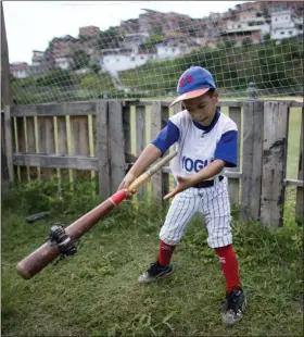  ?? ARIANA CUBILLOS — THE ASSOCIATED PRESS ?? In this photo, a boy swings a baseball bat using a donut to loosen his muscles during a practice session at the Brisas de Petare Sports Center in Caracas, Venezuela. More than 100boys train daily on the baseball field using old bats, balls and gloves, in hopes of achieving a profession­al baseball career in the United States.